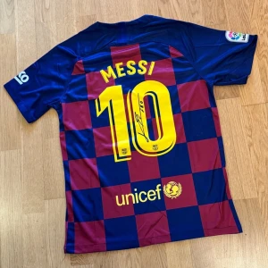 FC Barcelona Messi signerad autograf fotbollströja - Hej, säljer min Lionel Messi tröja jag har haft ett litet tag hängandes på väggen. Behöver samla ihop pengar för en bil så blir av med lite saker. Denna mäktiga samlarobjektet behöver hitta sig ett nytt hem ❤️💙. Köpt på tradera ett tag sedan (3999kr) där säljaren påstod sig har träffat leo själv och fått den signerad. Visar på sista sliden. Tröjan har inget certifikat och därför det låga priset. En med certifikat/äkthetsbevis går för 15.000kr+. Tröjan är i storlek M och medföljer ingen ram. 
