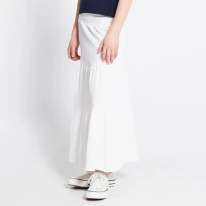 Vit långkjol med volang - Säljer en vit långkjol med bred resår i midjan och volangdetaljer. Kjolen har en luftig och flowy känsla, perfekt för varma dagar. Enkel att matcha med sneakers eller sandaler för en chill look. Orginalpris 200