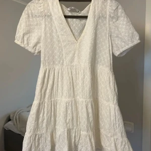 Vit kort klänning från Zara - Superfin vit kort klänning från Zara med broderade detaljer och v-ringning. Klänningen har puffiga korta ärmar och volangig kjol, perfekt för sommarens alla tillfällen men även till studenten 💞💞