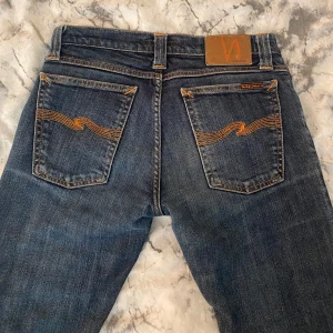 Mörkblå jeans från Nudie Jeans - Lågmidjade utsvängda jeans från Nudie jeans, omsydda hos skräddare och även sprättade nertill.                                    Midjemått rakt över: 34 cm. Innerbenslängd: ca 77 cm❣️