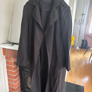 Svart trenchcoat från Rut&Circle - Säljer en svart trenchcoat från Rut&Circle med klassisk krage och långa ärmar. Jackan har en stilren och tidlös design som passar perfekt till många olika outfits.