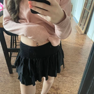 Svart volangkjol med resårmidja - Säljer en svart kortkjol med volanger och bred resår i midjan. Kjolen har en luftig och lätt känsla, perfekt för att styla med olika toppar. Enkel men ändå söt design som ger en trendig look.