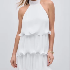 Vit halterneckklänning med volanger - Säljer denna slutsålda vita halterneckklänning med volangdetaljer i flera lager.  Aldrig använd, säljer då den inte riktigt passade! Kan sänka pris vid snabbt köp❣️❣️