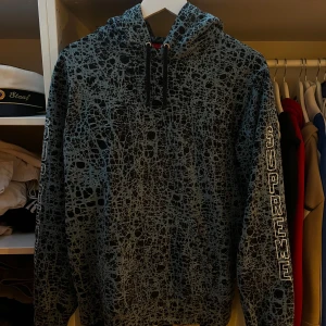 Supreme Hoodie - Säljer en Supreme hoodie i svart och blå med unikt abstrakt mönster och tryckt logga på ärmarna. Tröjan har huva med dragsko och är tillverkad i 100% bomull. Köpt i london på supreme för 3-4 år sedan. Kvitto ska finnas! Oklart vad en sån här går för idag men jag testar o ser vad man kan få för den! Väldigt ovanlig, hittade en sån här på ”StockX” för 4000 för nått år sedan. Toppskick och grymt material. tjockt och rejält! Sista bilden är från StockX där man ser värdet på de.Väldigt sällsynt tröja