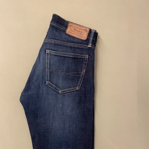 Mörkblå  jeans från Polo Ralph Lauren - Snygga mörkblå jeans från Polo Ralph Lauren, modell The Eldridge Skinny. Klassisk femficksdesign, läderpatch bak och diskreta slitningar för en cool look. Perfekta för dig som gillar smal passform och stilrena detaljer.