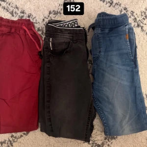 Tre par byxor i olika färger och stilar - Säljer tre par byxor: ett par vinröda mjukisbyxor med dragsko, ett par svarta jeans och ett par blå jeans med resår i midjan. Perfekta för dig som vill ha variation i garderoben!