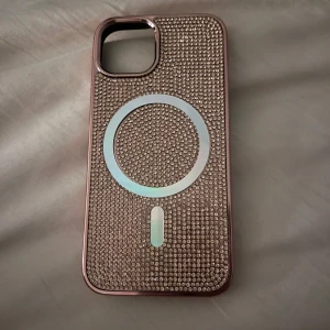 Glittrigt mobilskal med MagSafe - Säljer ett snyggt mobilskal med glittriga stenar och MagSafe-kompatibilitet. Skalet är rosa med massor av små stenar som ger en lyxig känsla. Perfekt för dig som vill ha något extra till mobilen!