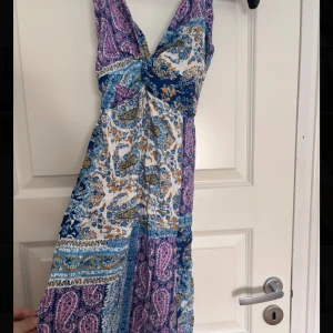  Sommarklänning med paisleymönster - Säljer en lång klänning från Zara. Den har  tunna band och klänningen har blommönster. Klänningen har knyt vid bysten och är tillverkad i ett lätt och luftigt material. Finns en dragkedja på sidan.