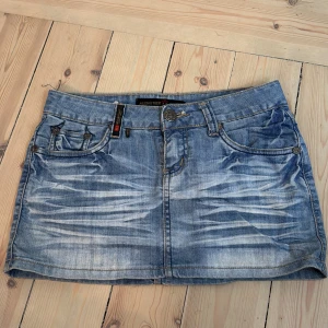 Jeanskjol  - Säljer en klassisk blå jeanskjol från ”Musketeer” med slitningar och femficksmodell. Kjolen har knapp- och dragkedjestängning framtill samt dekorativa bakfickor med broderade detaljer. 💞✌🏽😋