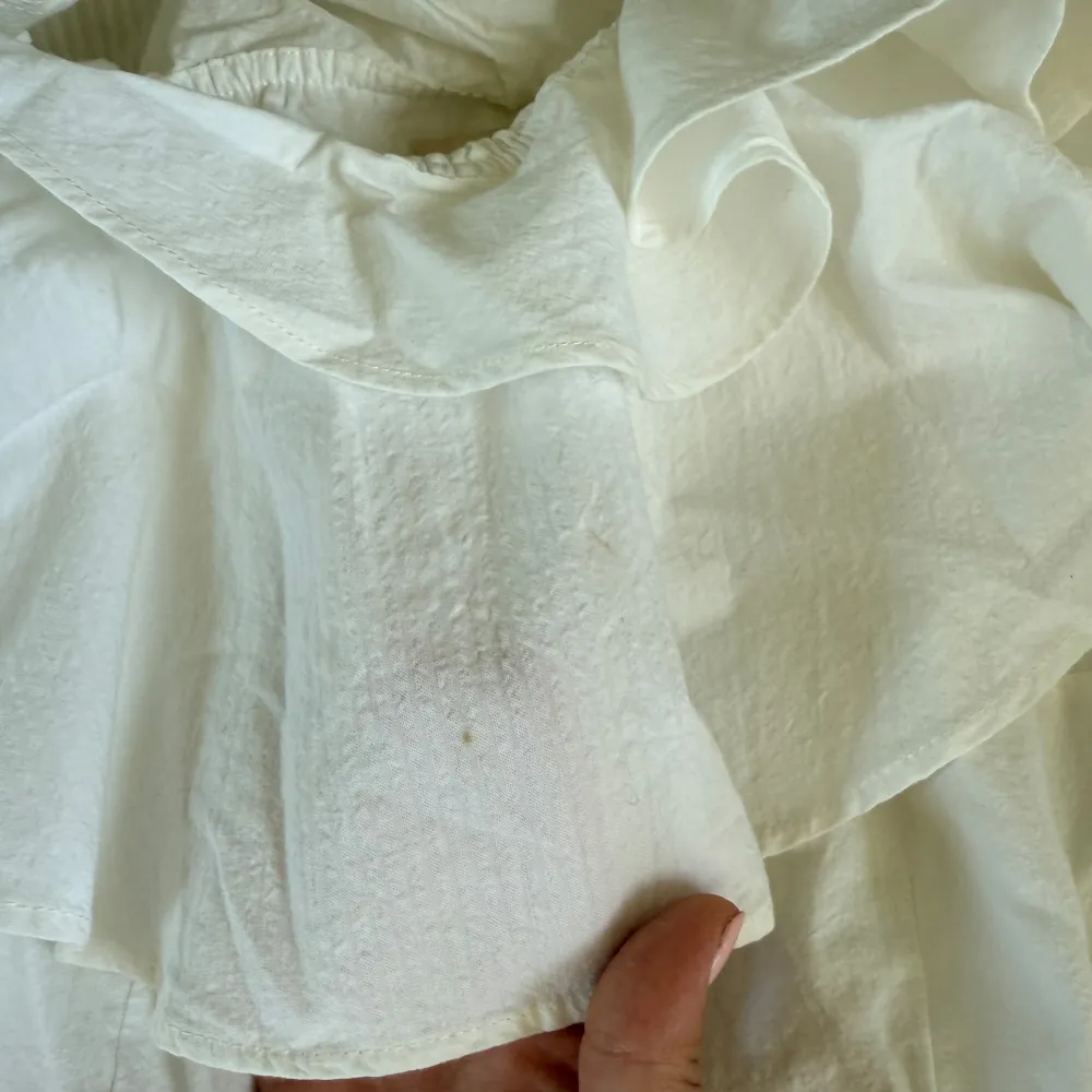 Säljer en vit kortklänning med offshoulder och stor volangdetalj över axlarna. Klänningen har en figurnära passform och dragkedja i sidan som har gått sönder i sömmarna, men väldigt lätt att sy. Perfekt för studenten eller sommarens tillfällen när du vill sticka ut lite extra.. Mekot.