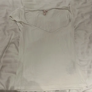 Nelly topp - Vit t shirt från nelly med spets detaljer längs urringningen, har använt fåtal gånger men är i jättefint skick! 