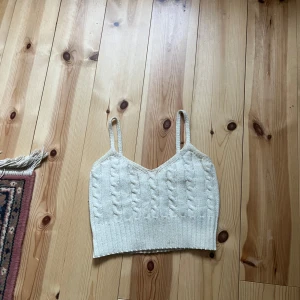 Vit stickad linnetopp från SHEIN - Säljer en söt vit stickad linnetopp från SHEIN med smala axelband och kabelstickat mönster. Toppen är croppad och har en ribbad nederkant. Perfekt att styla till jeans eller kjol!