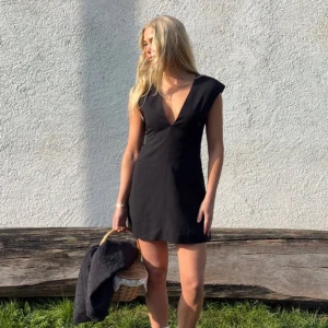 Moa Mattsson X NA-KD Svart kortklänning med v-ringning  - Säljer en svart kortklänning med djup v-ringning och breda axelpartier. Klänningen har en figurnära passform och är perfekt för dig som vill ha en stilren och enkel look. Passar till många olika tillfällen. Klänningen är helt oanvänd och lappen sitter kvar 