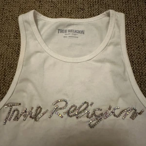 Vit linnetopp från True Religion med strass - Säljer en vit linnetopp från True Religion med glittrig strasslogga framtill. 