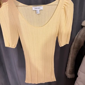 Ljusgul ribbad topp från & Other Stories - Supersöt ljusgul ribbad topp från & Other Stories med korta ärmar och rundad urringning. Toppen har en slim passform och är tillverkad i ett mjukt, stretchigt material som sitter snyggt på kroppen. Aldrig använt tyvärr, nypris 790kr