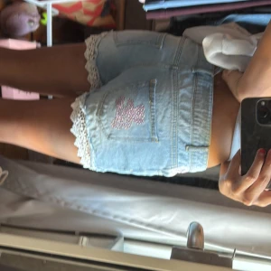 jeansshorts med spetsdetaljer - supersöta lågmidjade shorts med spetsdetaljer och rosa paljetter. använt ett fåtal ggr och passae mig som är small. midjemått är 38 cm! pris kan diskuteras💕