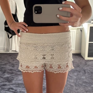 Spetsshorts - Supersöta beige shorts med virkade spetsdetaljer och blommigt mönster. Fina volangkanter i lager längst ner. Finns inga defekter. Pris kan diskuteras vid snabb affär💓