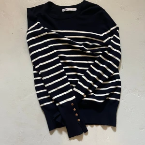 Randig topp från Zara - Finstickad randig tröja från Zara med gulddetaljer vid handleden! Använd en del men i fint skick💕storlek m men skulle säga att den är mindre i storlek!!