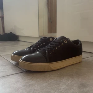 Svarta sneakers med beige sula - Snygga svarta sneakers med glansig tå och beige, lite tjockare sula. Skorna har klassisk snörning och metallfärgade öljetter. Perfekta för dig som gillar en stilren och enkel look med en twist. Passar till det mesta och är riktigt bekväma.