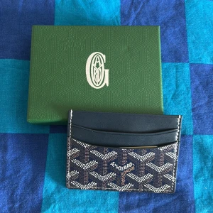 G4yard korthållare i svart och brunt - Snygg korthållare från Goy4rd med klassiskt mönster i svart, brunt och vitt. Kompakt design med flera kortfack och exklusiv känsla. Perfekt för dig som vill ha stilren och lyxig accessoar i fickan.