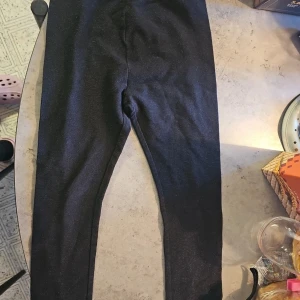 Svarta glittriga leggings från H&M - Snygga svarta leggings från H&M med glittrig finish som ger en cool look. Stretchigt material och bekväm resår i midjan. Perfekta för dig som vill sticka ut lite extra med en touch av glitter.