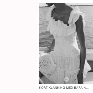 Vit kort klänning med volang från Zara - Superfin vit kort klänning från Zara med broderade hål, volang vid axlarna, smockad överdel och offshoulder-modell. Aldrig använd! 