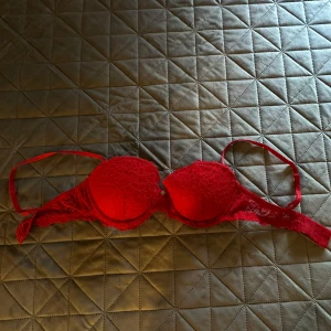 Röd spetsig bh från H&M - Snygg röd bh från H&M med spetsdetaljer och vadderade kupor. Den har bara legat och aldrig kommit till användning, därav säljer jag den! 