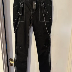 Byxa från Lucyfer storlek L ( men är som M/L)  - Helt ny lite rockigare byxa från Lucyfer. Storlek L, men tycker den är som M/L. Material i skön bomullstretch. Midjevidd 85,5 cm. Stussvidd ca 98 cm.