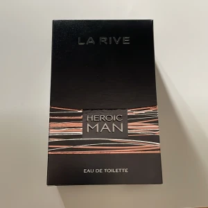 Helt ny La Rive Heroic Man Eau de Toilette 100ml - La Rive Heroic Man Eau de Toilette är en maskulin parfym i en stilren, rektangulär glasflaska med silverfärgad metallkork. Doften kommer i en svart kartong med koppar- och silverdetaljer. Innehåller 100 ml och har en varm bärnstensfärgad vätska.