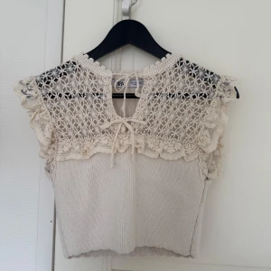 Beige stickad blus med spets från Zara - Supersöt beige stickad blus från Zara med spetsdetaljer och volang vid axlarna. Överdelen har ett vackert virkat mönster och knytning fram vid halsen. 🤍🤍