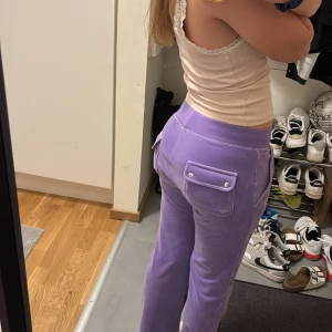 Lila juicy byxor  - Säljer ett par lila mjukisbyxor i mjukt material med bred resår och snörning i midjan. Byxorna har fickor fram och bak, där bakfickorna har lock med tryckknappar. Perfekta för chill dagar eller när du vill vara extra comfy. Jag har själv sytt upp dom men jag är 160 och dom är perfekta i längden. Använt ett par fåtal gånger.