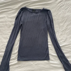 Mörkblå långärmad topp Gina Tricot - En enkel och stilren mörkblå långärmad topp från Gina Tricot. Modellen är tight med rund halsringning och tillverkad i mjuk bomullsmix. Långa ärmar med en slits i slutet.