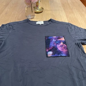 Svart t-shirt från Limitato med tryck - Cool svart t-shirt från Limitato med ett stort färgstarkt tryck på bröstet. Trycket har lila, blå och rosa toner och en handskriven text. T-shirten har rund hals och klassisk passform. Perfekt för dig som vill sticka ut lite extra. En utav limitatos första kollektioner någonsin.