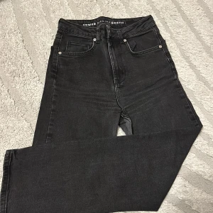 Svarta skinny jeans med hög midja - Snygga svarta skinny jeans med hög midja och klassisk femficksdesign. Jeansen har en stilren look och passar perfekt till sneakers eller boots. Materialet är stretchigt för extra komfort och de har dragkedja och knapp framtill.