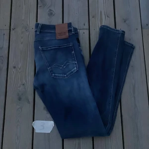 Replay Anbass blå slim fit jeans 29-32 - Säljer ett par Replay Anbass jeans i snyggt tvättad blå färg. Jeansen har klassisk femficksdesign, diskreta slitningar och logga på bakfickan. De är tillverkade i mjukt jeansmaterial och har en slim passform som sitter riktigt bra.