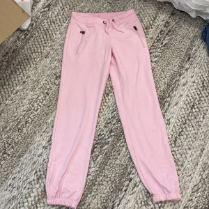 Rosa mjukisbyxor med dragkedjor - Ljusrosa mjukisbyxor med resår och snörning i midjan. Byxorna har dragkedjor på fickorna och resår vid bensluten. 