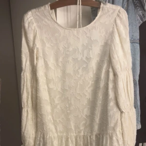 Vit blommig långärmad klänning - Romantisk vit klänning med subtilt blommigt mönster och långa puffärmar. Den har lite mer öppen rygg, har andvänt 1 gång 