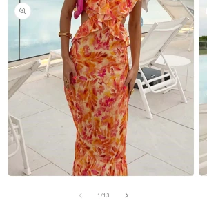 Blommig långklänning med volang - Superfin långklänning i blommigt mönster med orange, rosa och gula toner. Klänningen har volangdetaljer upptill, öppen rygg med knyt och är ärmlös. Perfekt för sommarens alla tillfällen när du vill sticka ut lite extra. Denna är i nyskick med prislapp kvar då den ej hann komma i tid till när jag skulle använda den!💕ordinarie pris 835!