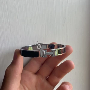 H armband - Armband med H märke: 📊 Färg: svart/silver  📏 Storlek: ca 19cm 📐 Mått: Mätte på 19cm  🧵 Material: Rostfritt stål (tror jag)  ♻️ Skick: Extremt bra, inga defekter   Hör av dig vid frågor! Tack🤩