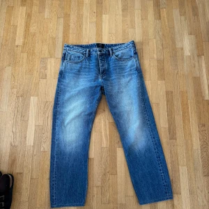 Blå raka jeans från Neuw - Snygga blå jeans från Neuw med klassisk femficksmodell och raka ben. Jeansen har en schysst tvätt med ljusa partier framtill och bak, samt subtila slitningar för en avslappnad look. Perfekta för dig som gillar en enkel och stilren vibe. Nypris 1299kr