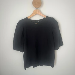 Svart topp med puffärm från 157 - En svart topp från 157 i 100% bomull med puffiga korta ärmar och rund halsringning. Har använts några gånger men är i fint skick. Hör av dig om det är något! 