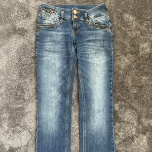 Blå lågmidjade jeans från LTB - Snygga blå jeans från LTB med straight passform och low waist. Jeansen har klassiska fickor fram och bak, dubbla knappar i midjan och slitna detaljer vid bensluten💕💕
