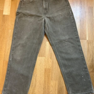 Brunt Carhartt jeansbyxor 36x32 - Säljer ett par brunt jeansbyxor från Carhartt i 100% bomull. Klassisk rak passform med normal midja och robust känsla. Byxorna har snygga detaljer som Carhartt-logga på knappar och ficka. Perfekta för dig som gillar streetwear och workwear vibes.