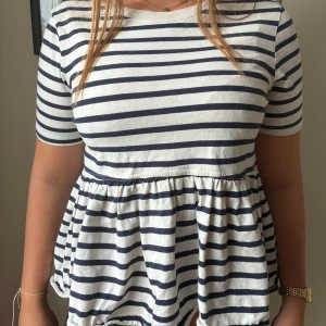 Randig topp från ZARA - Superfin randig topp från Zara med marinblå och vita ränder. Modellen har kort ärm, rund halsringning och volang nedtill som ger en avslappnad och söt look. Perfekt till jeans eller kjol för en fräsch stil. Säljer på grund av att den inte kommer till användning. Pris kan diskuteras!!