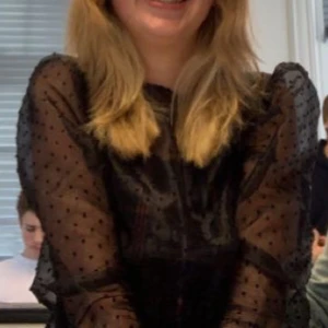 Svart transparent prickig blus - Säljer en svart transparent blus med långa puffärmar och små prickar över hela tyget. Blusen är croppad med resår i midjan och har en rund halsringning. Jag har tyvärr klippt bort lappen där man ser storlek och märke (den syntes för mycket när man hade den på sig), men jag skulle gissa att den är i storlek M.