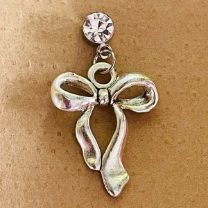 By prisförslag- 1 st Örhänge med rosett och strass - Snyggt örhänge i silverfärgad metall med en glittrande strass-sten upptill och en hängande rosett som ger en söt och trendig vibe. Perfekt accessoar för att lyfta din look med lite extra bling och charm.