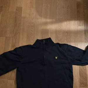Svart tröja med dragkedja från Lyle & Scott - Säljer en stilren svart tröja från Lyle & Scott med halv dragkedja och deras ikoniska logga på bröstet. Perfekt för en avslappnad look. Tröjan har långa ärmar och en bekväm passform. Ganska använd 7/10 skick. Ny pris 1299 mitt pris 399