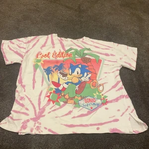Rosa och vit t-shirt med Sonic-motiv från Zara - Cool t-shirt från Zara med ett färgglatt Sonic the Hedgehog-tryck. Den har ett rosa och vitt batikmönster och texten 'Cool Edition'. Perfekt för alla Sonic-fans!