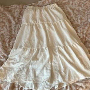 Vit kjol från Shein - Säljer en vit kjol från Shein med elastisk midja och flera lager som ger en fin volangeffekt. Perfekt för varma dagar och kan enkelt matchas med olika toppar 💕