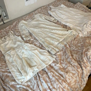 Tre vita klänningar - Säljer tre vita klänningar i olika stilar. En ärmlös med broderade blommor, en långärmad spetsklänning och en axelbandslös med volangdetalj. Perfekta för sommaren! 